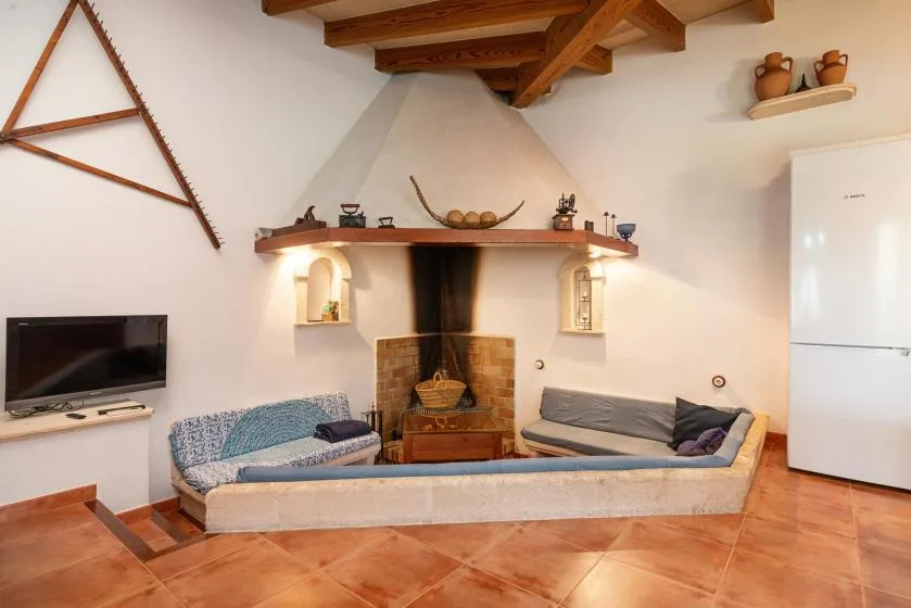 A living room with built-in seating around a fireplace and a television on the wall.