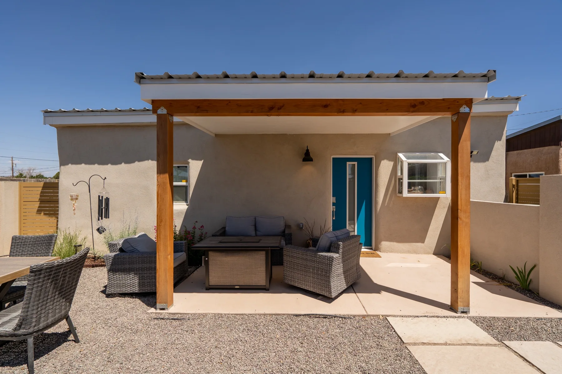 Un patio sombreado con asientos y una mesa junto a la casa.