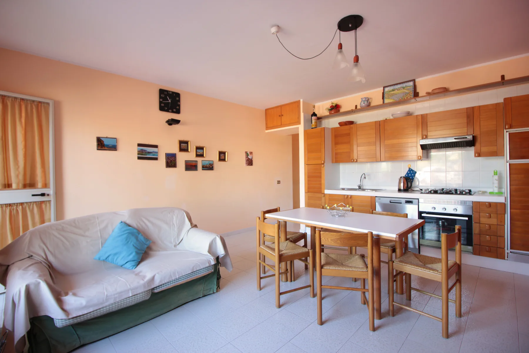 A living and dining area with a sofa, table, and adjoining kitchen.