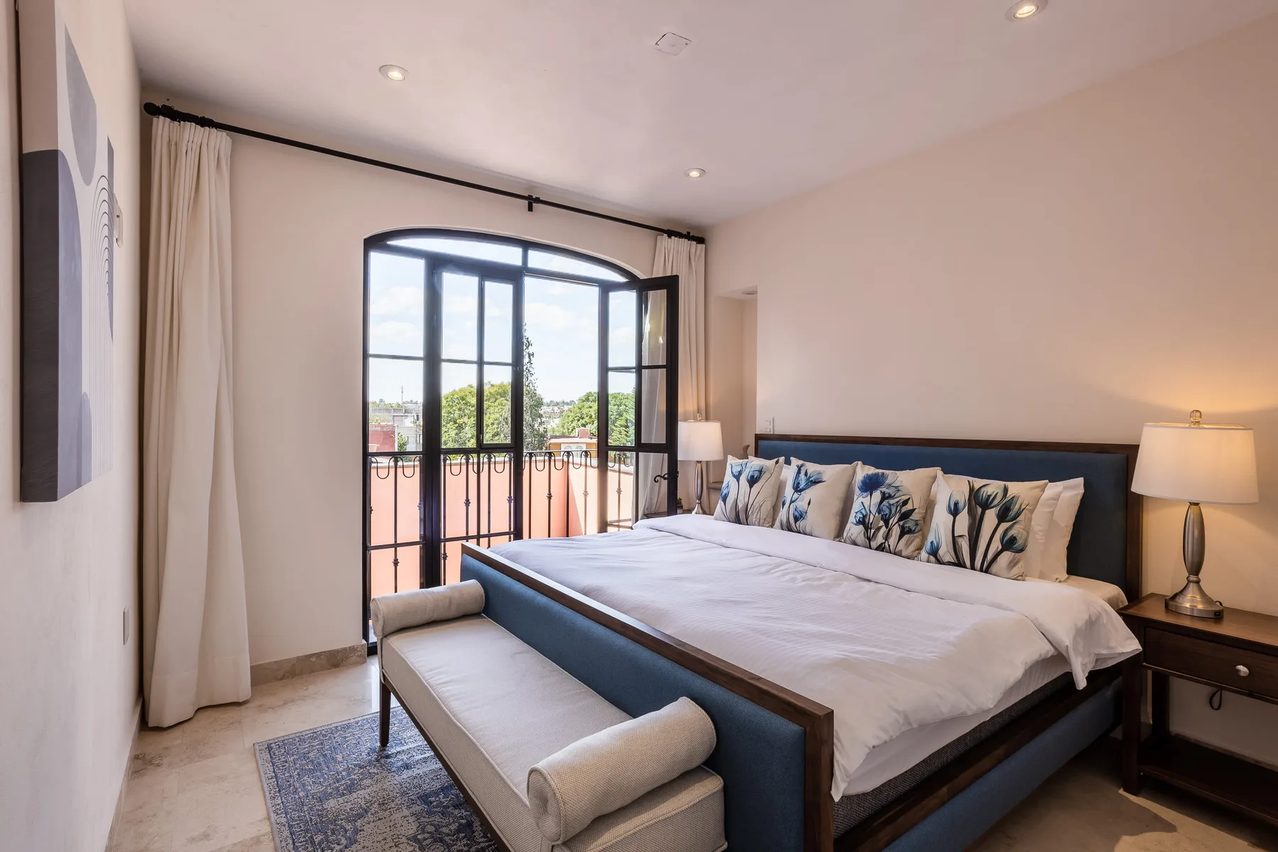 A bedroom with a large bed and arched glass doors opening to a balcony.