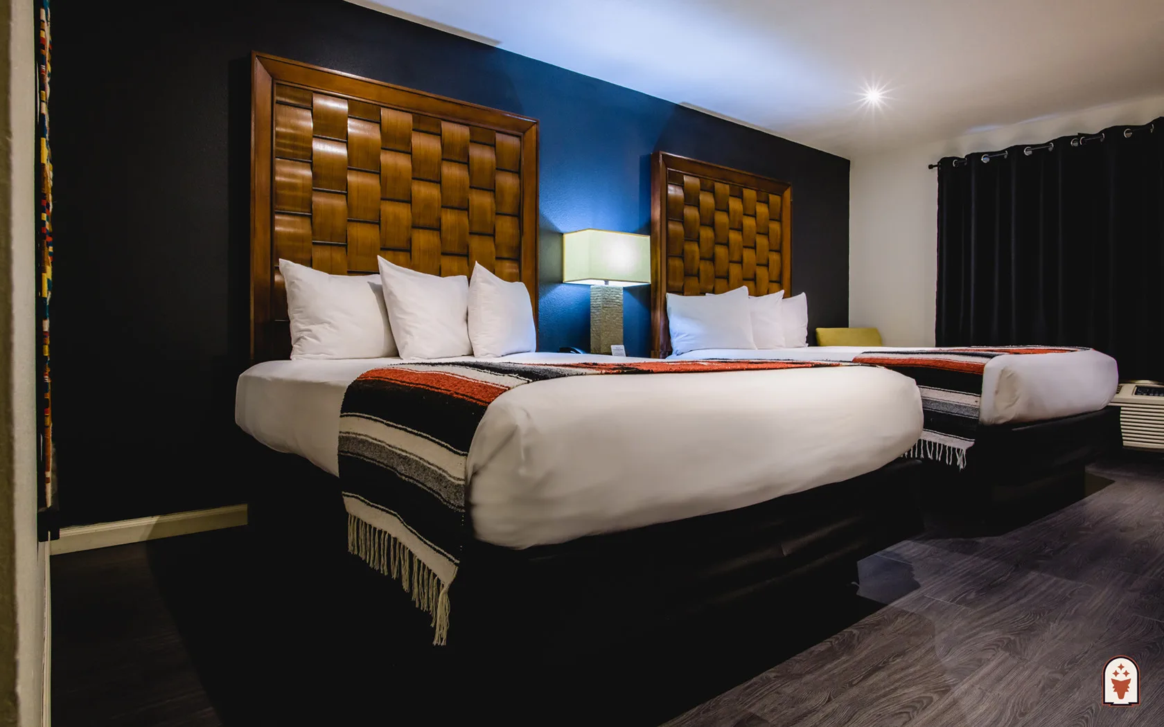 Habitación con dos camas queen, cortinas azules y mantas de estilo del suroeste