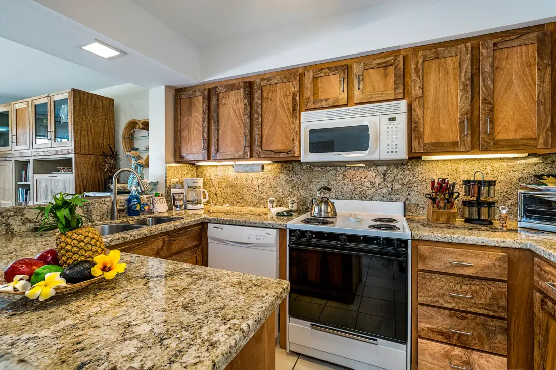 Una cocina con gabinetes de madera, una estufa y encimeras de granito.