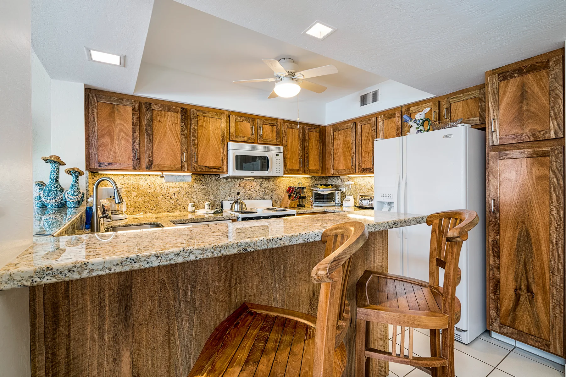 Una cocina con gabinetes de madera, una encimera y asientos de barra.