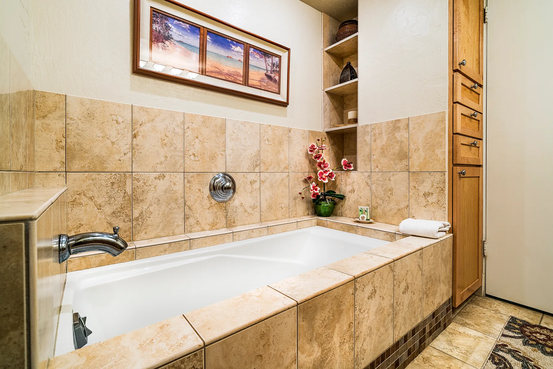Un baño con azulejos, una bañera empotrada y un cuadro enmarcado encima.