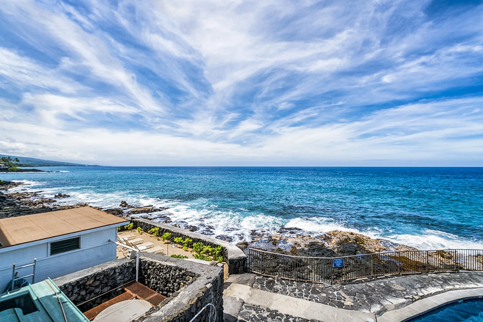 Terraza costera con vistas al océano y olas rompiendo junto a la costa rocosa.