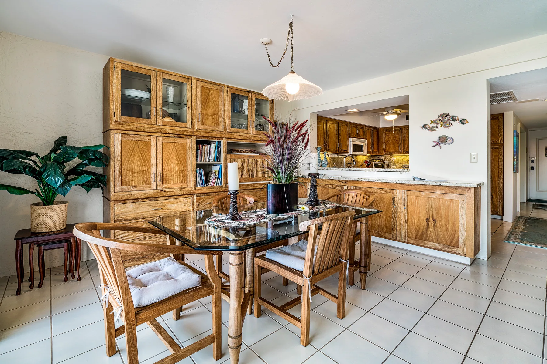Un comedor con una mesa de vidrio junto a gabinetes de madera y una encimera de cocina.