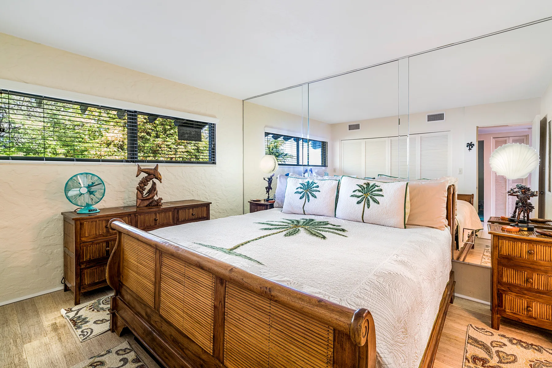 Un dormitorio con una cama grande, muebles de madera y una pared con espejo.