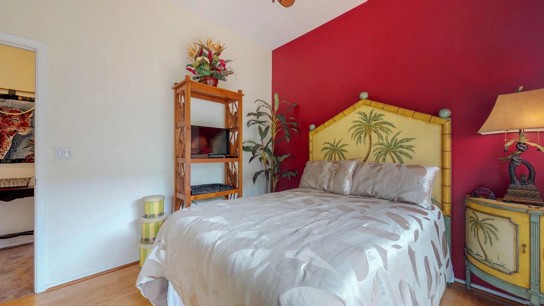 Un dormitorio con una cama junto a una pared roja y una estantería de madera.