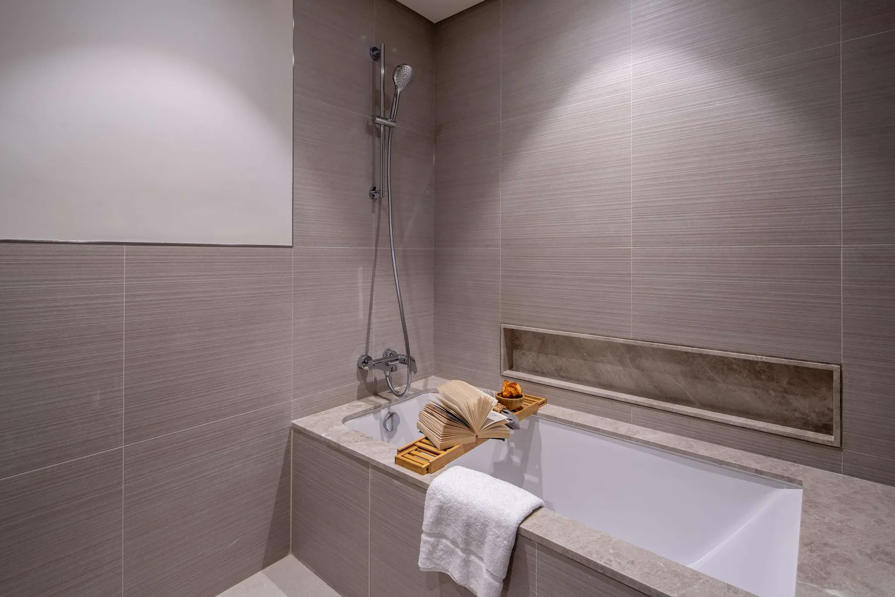 Un baño con bañera, ducha de pared y toallas dobladas.