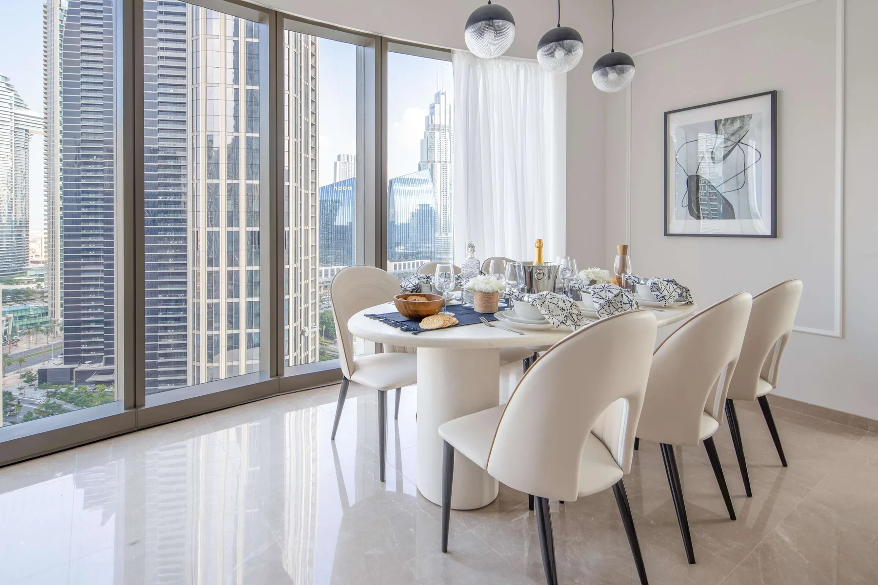Un comedor luminoso con una mesa puesta junto a ventanales con vistas a edificios de la ciudad.