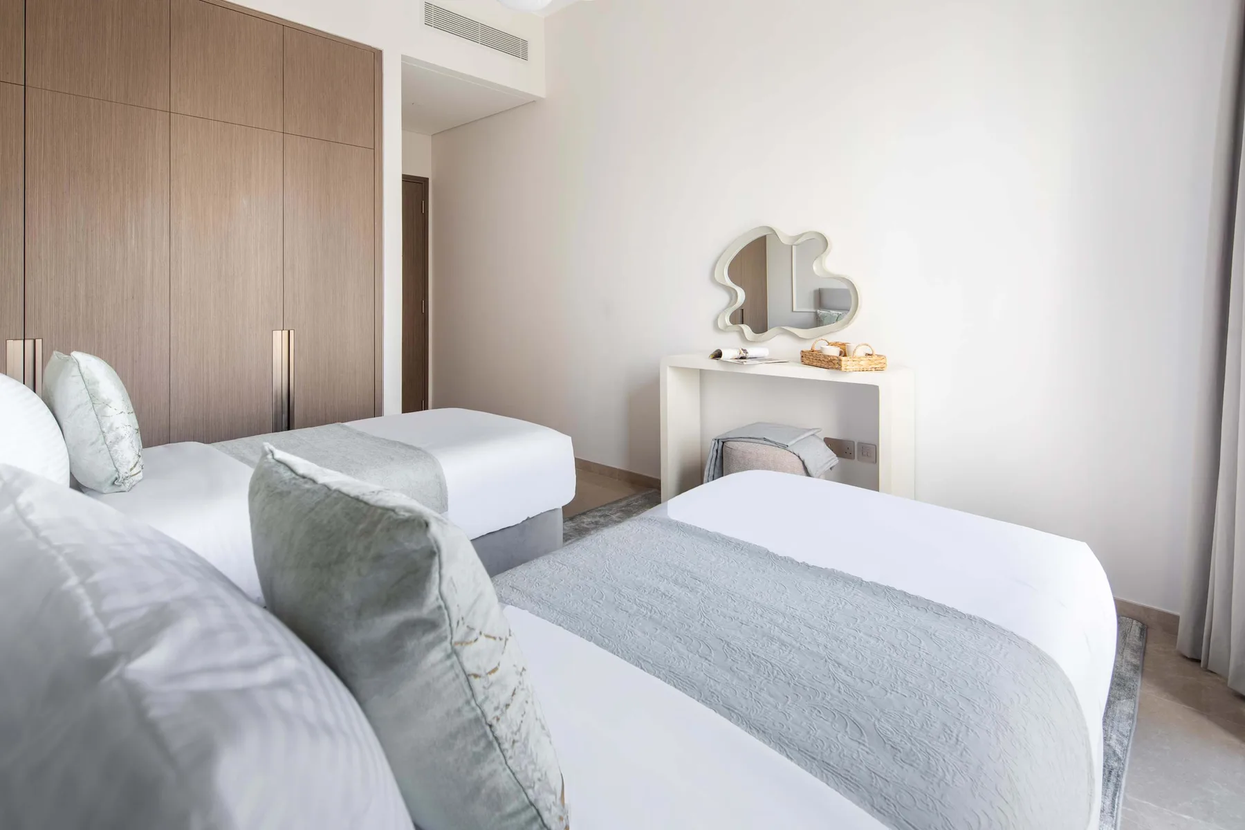 Un dormitorio luminoso con dos camas y una pequeña mesa de tocador.