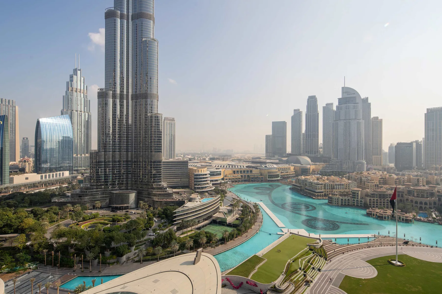 Un horizonte urbano se alza sobre una piscina turquesa y jardines.