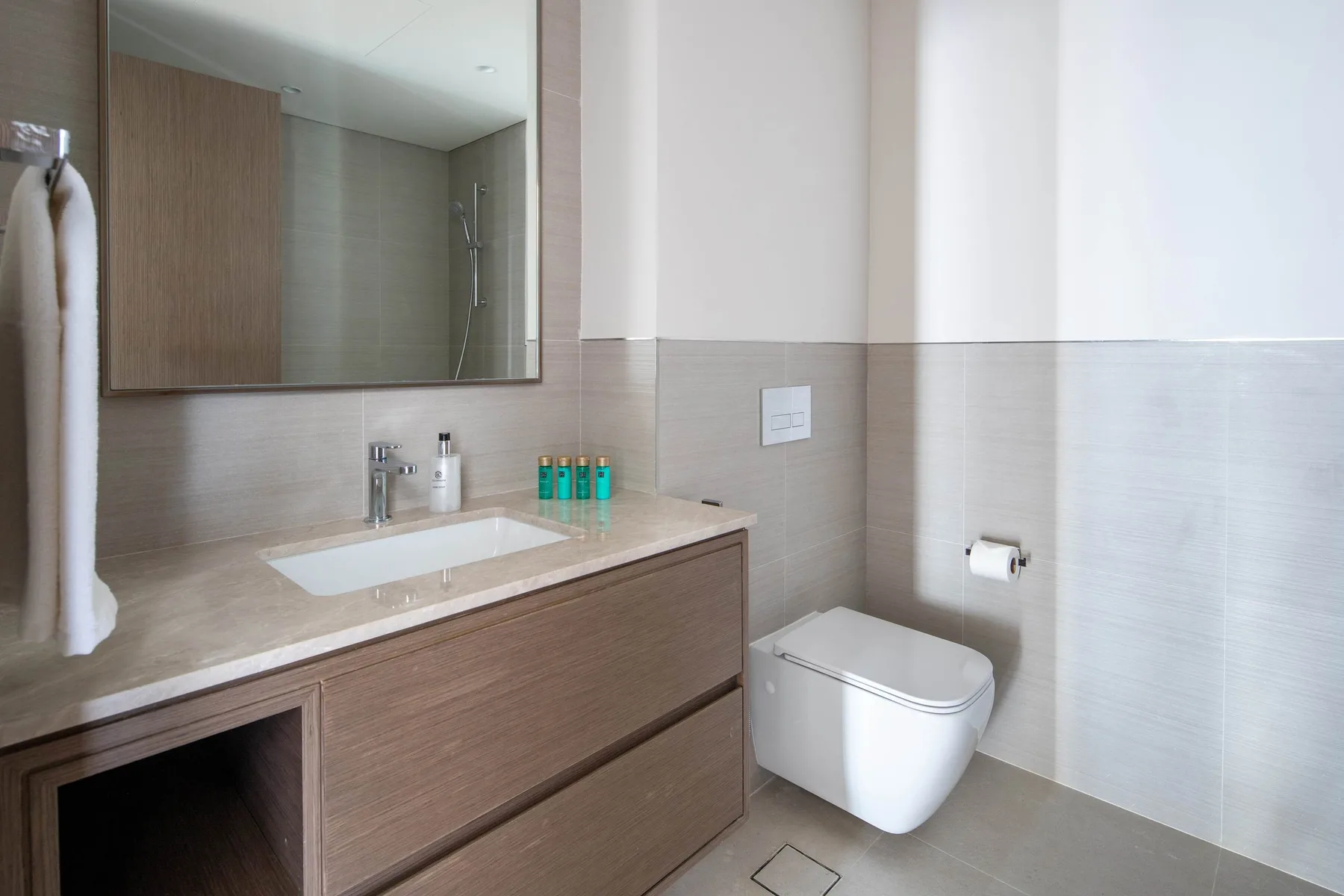 Un baño moderno con lavabo, espejo amplio e inodoro suspendido.
