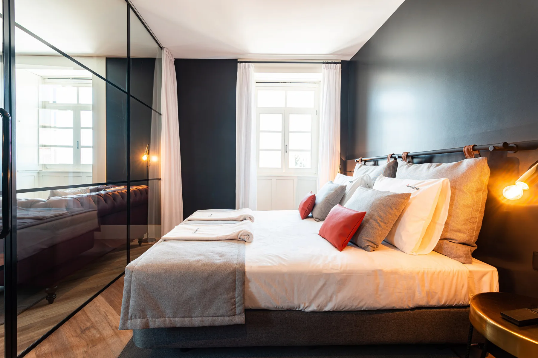 Un dormitorio con una cama y almohadas junto a un armario con espejo.