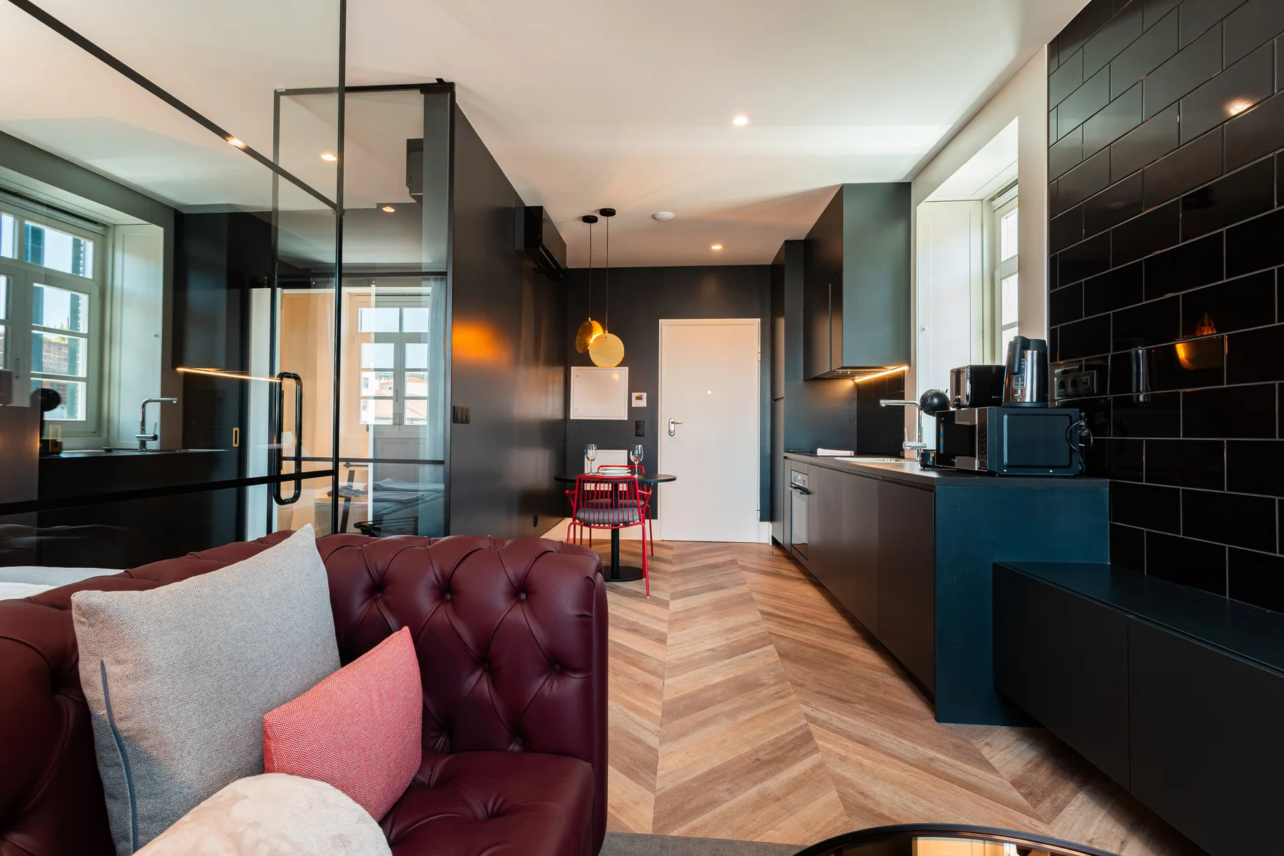 Una cocina y sala de estar modernas con gabinetes oscuros y asientos.
