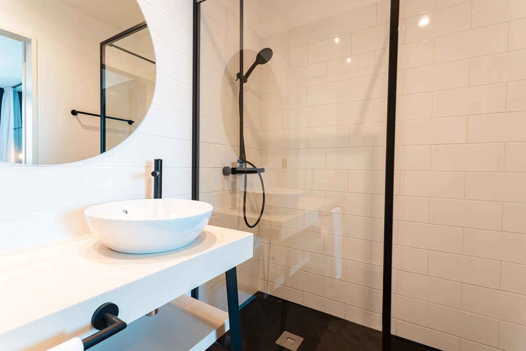 Un baño luminoso con lavabo sobre encimera y ducha con paneles de vidrio.