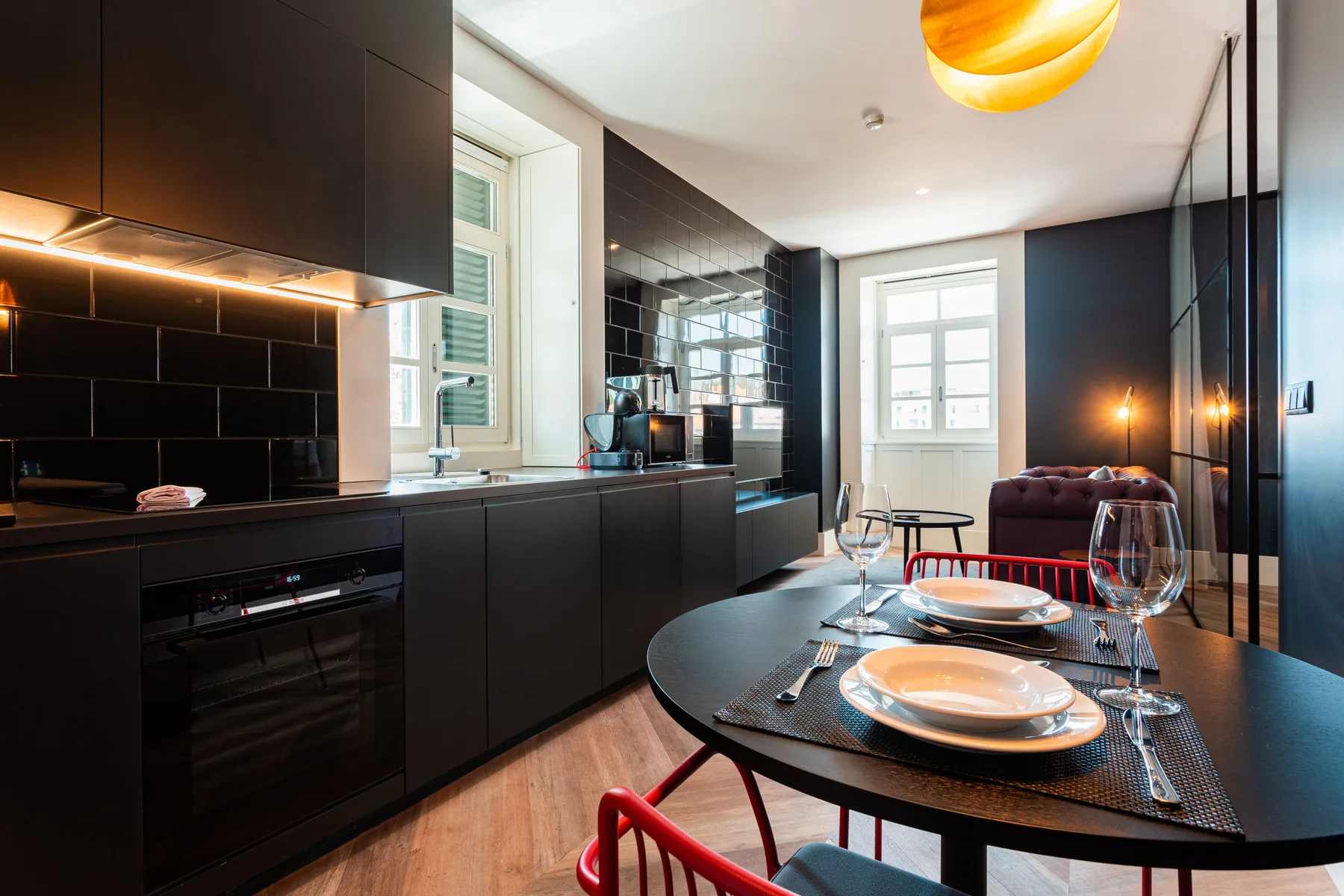 A modern kitchen and dining area with dark cabinetry and a set table.