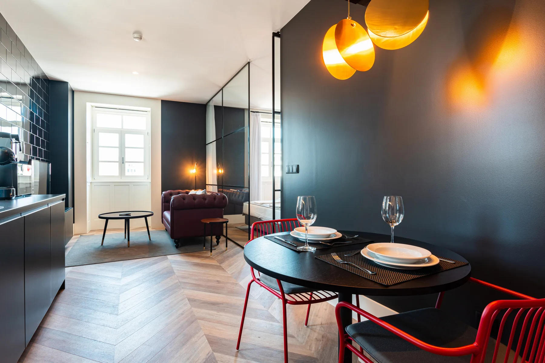 Un espacio abierto de comedor y sala de estar con mesa, asientos y lámparas colgantes.