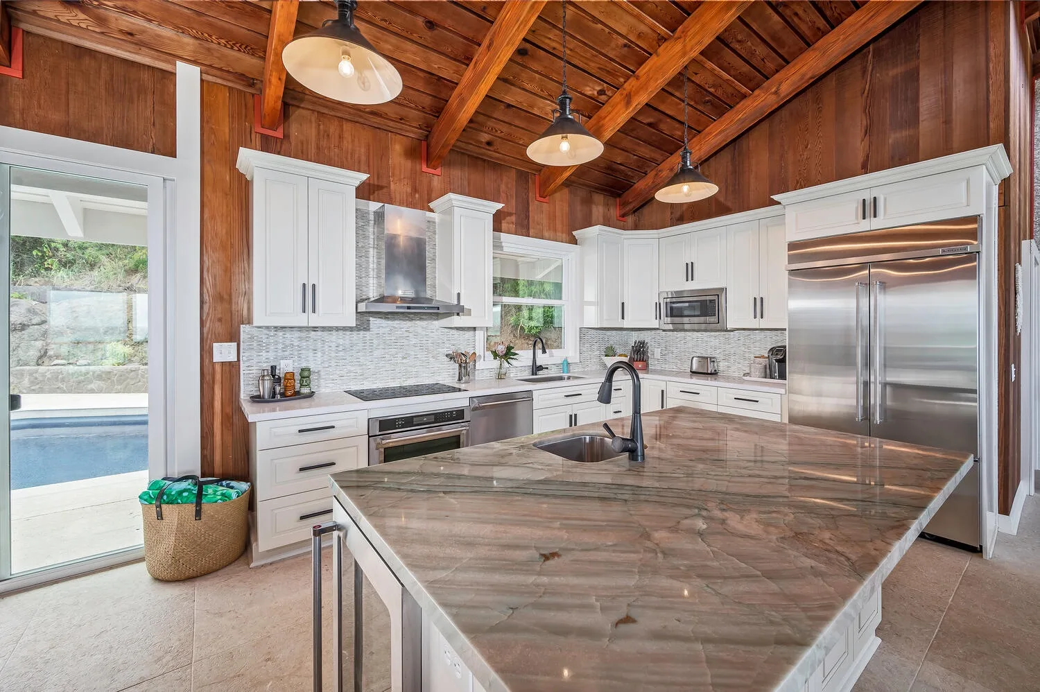 A spacious kitchen with white cabinetry, stainless steel appliances, and a large island.