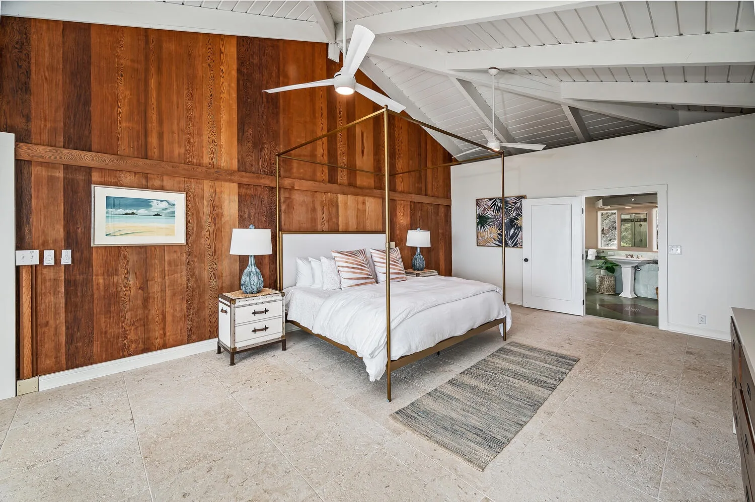 A bedroom with a bed beneath a high, angled ceiling and wood-paneled wall.