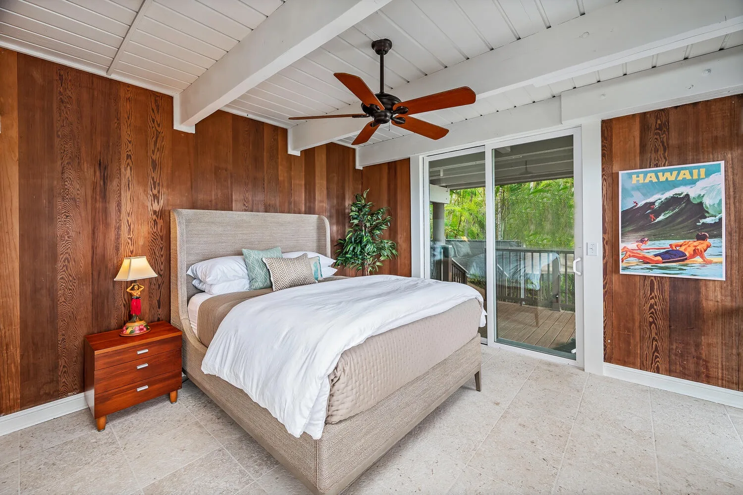 A bedroom with a neatly made bed and sliding glass doors opening to a balcony.