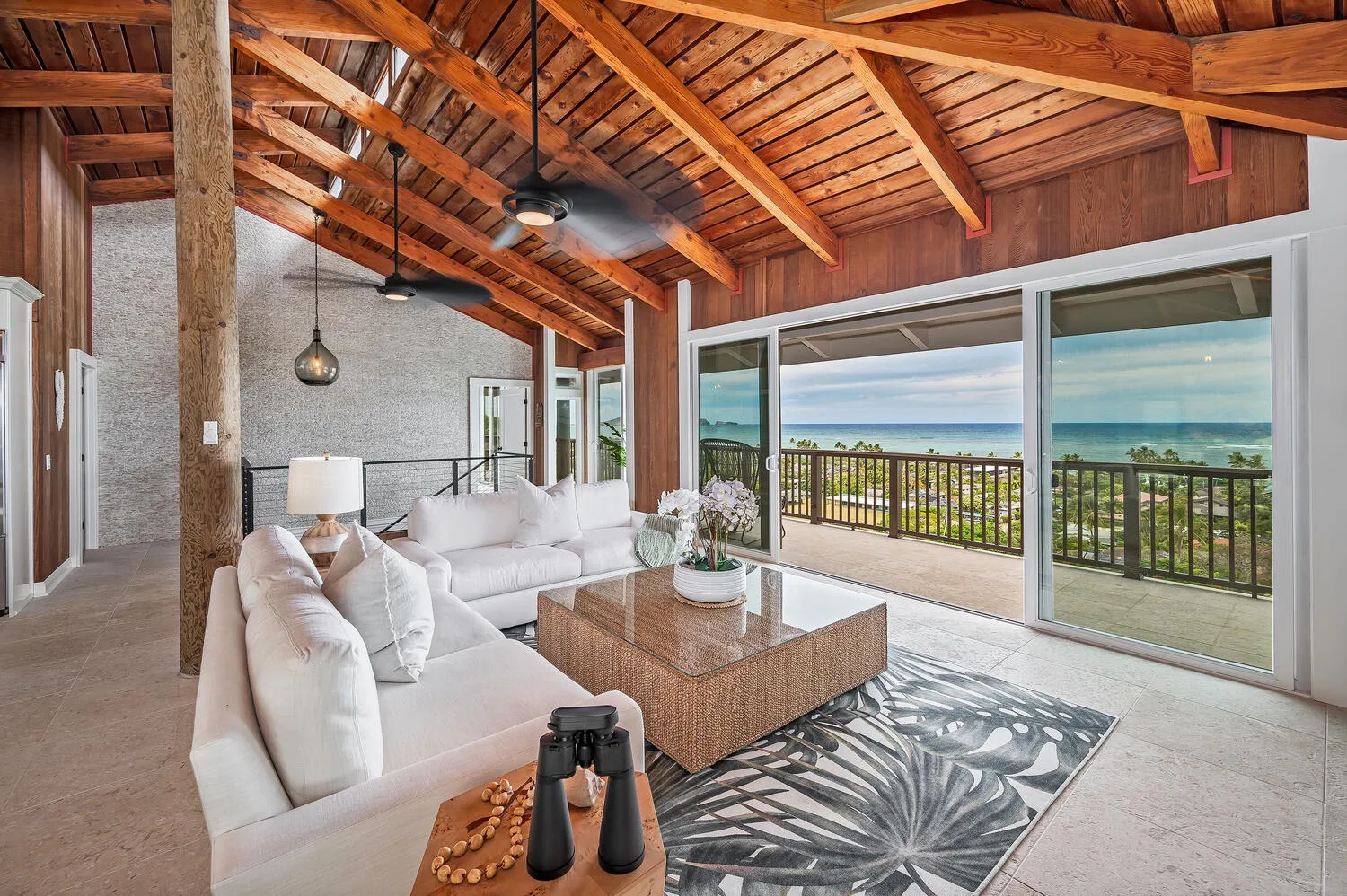 A bright living room opens onto a balcony with ocean views.