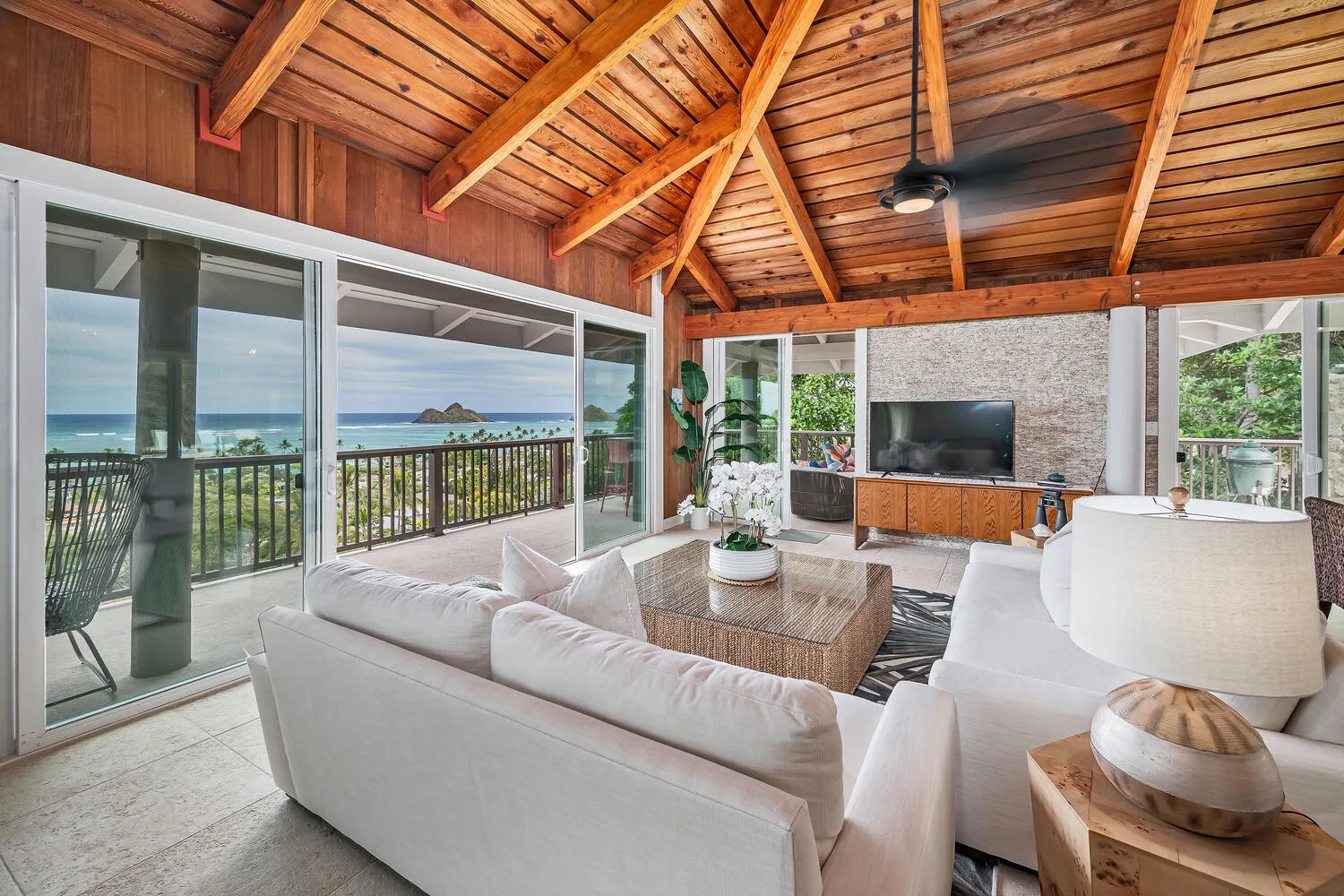 A bright living room opens onto a balcony with ocean views.