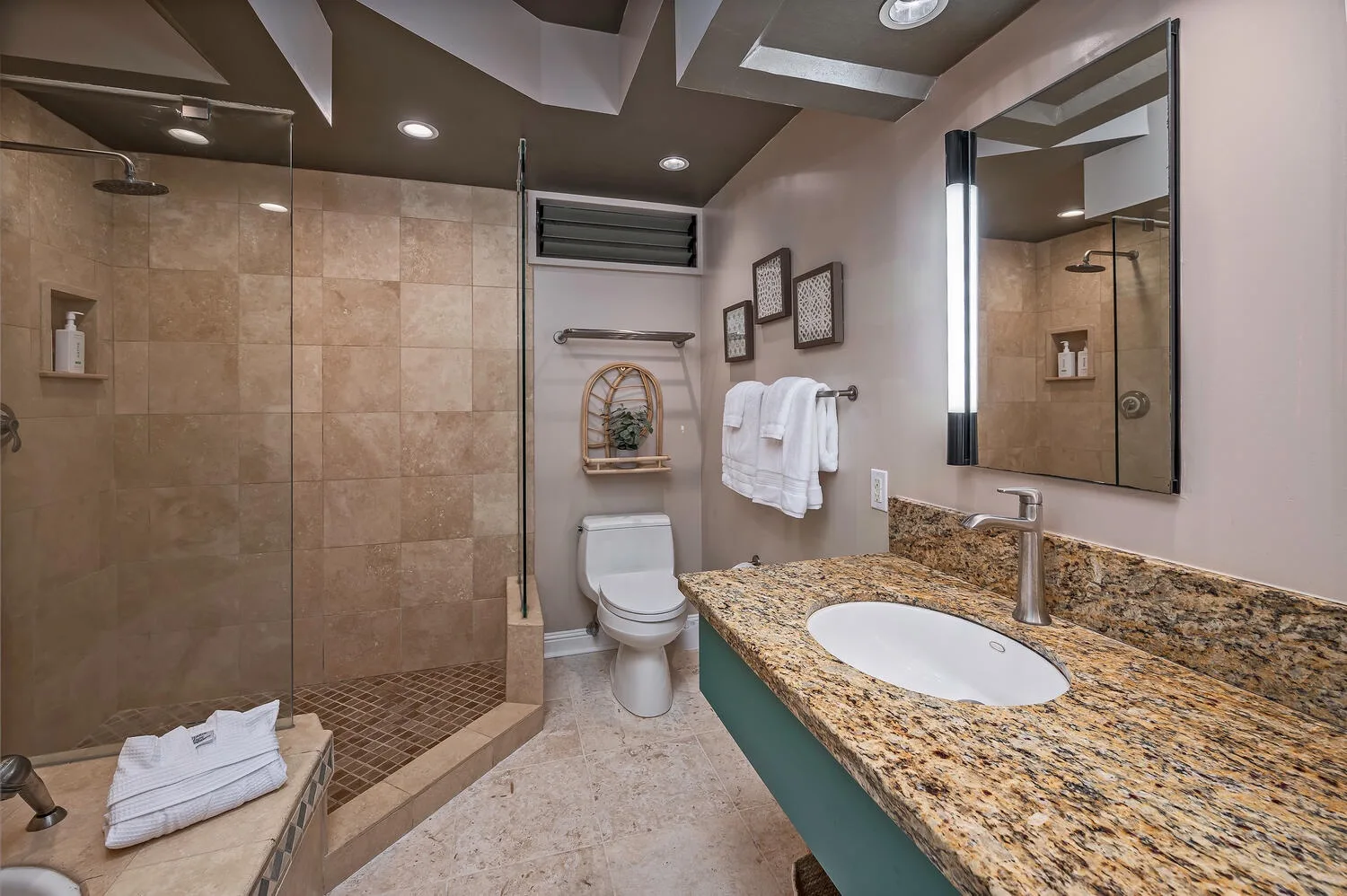 A bathroom with a tiled shower, toilet, and vanity.
