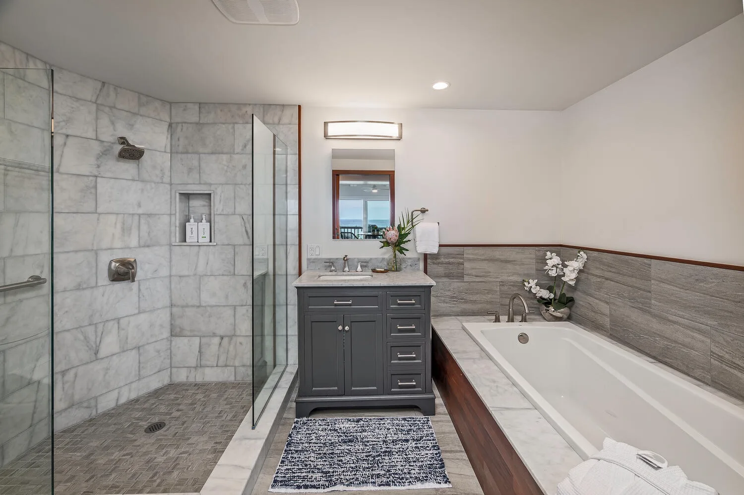 A bathroom with a glass-enclosed shower, vanity, and bathtub.
