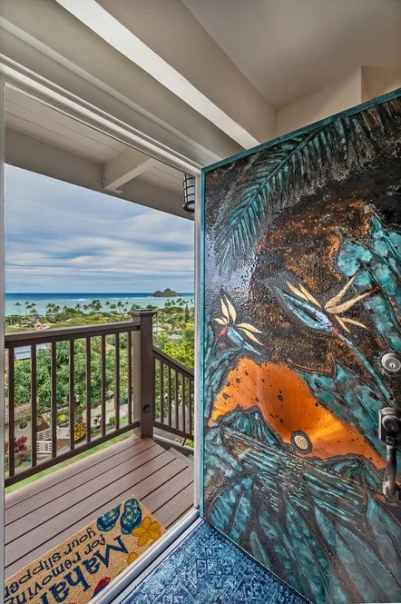 An open doorway leads to a balcony overlooking the ocean, with a colorful painted door.