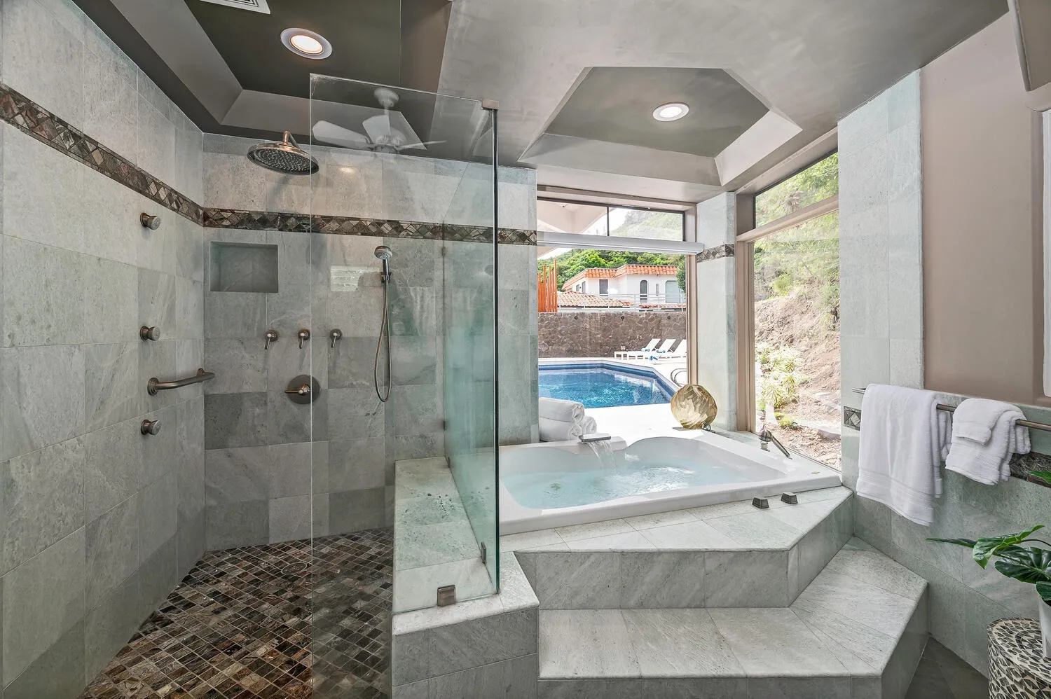 A spacious bathroom with a glass shower and a large soaking tub beside a window.