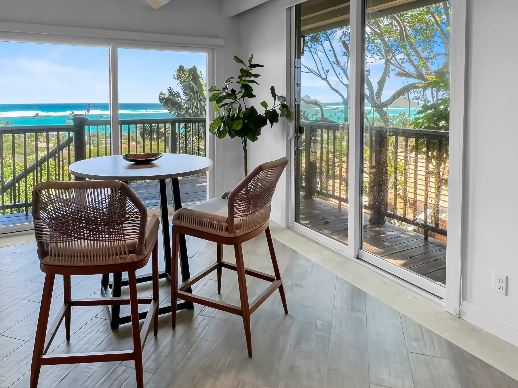 A bright dining nook with seating beside large windows overlooking the ocean.