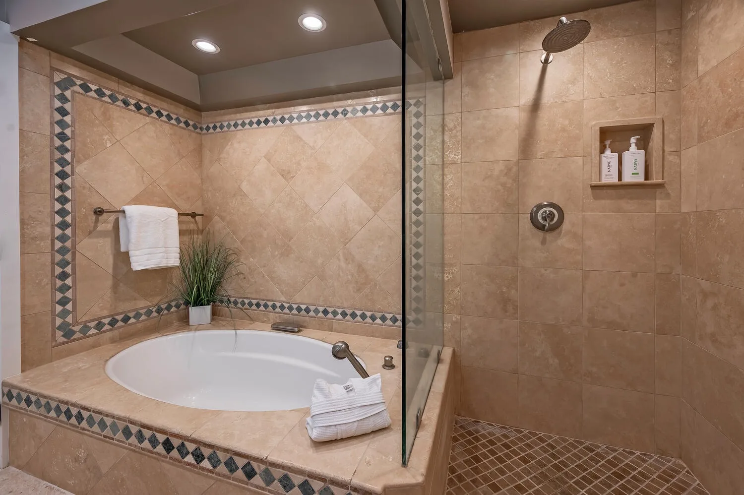 A tiled bathroom with a bathtub and a glass-partitioned shower.