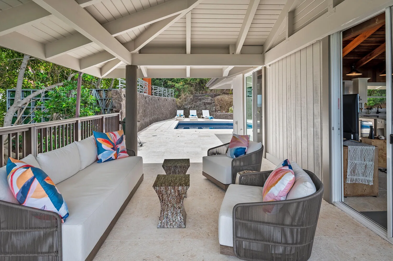 Una zona de estar exterior cubierta da a un patio con piscina.