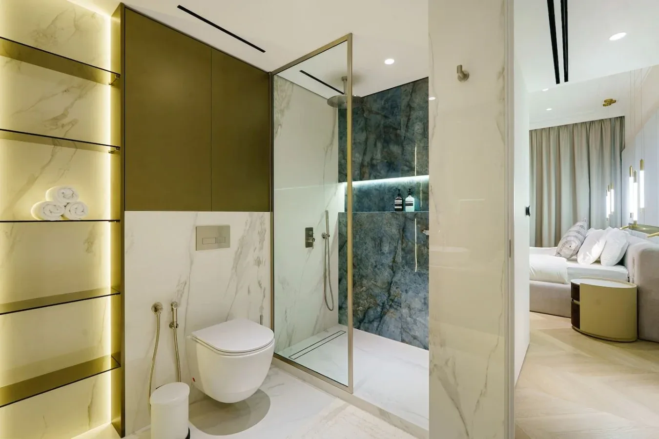 Un baño moderno con una ducha de vidrio junto a un dormitorio abierto.