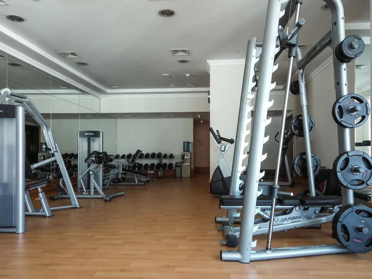 Un gimnasio con máquinas de pesas y pesas libres distribuidas por la sala.