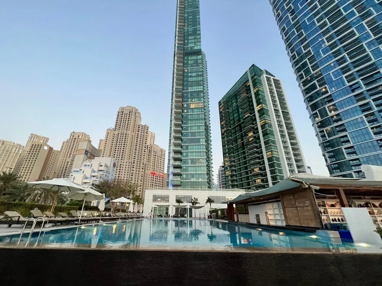 Una piscina al aire libre está rodeada de edificios modernos y altos.