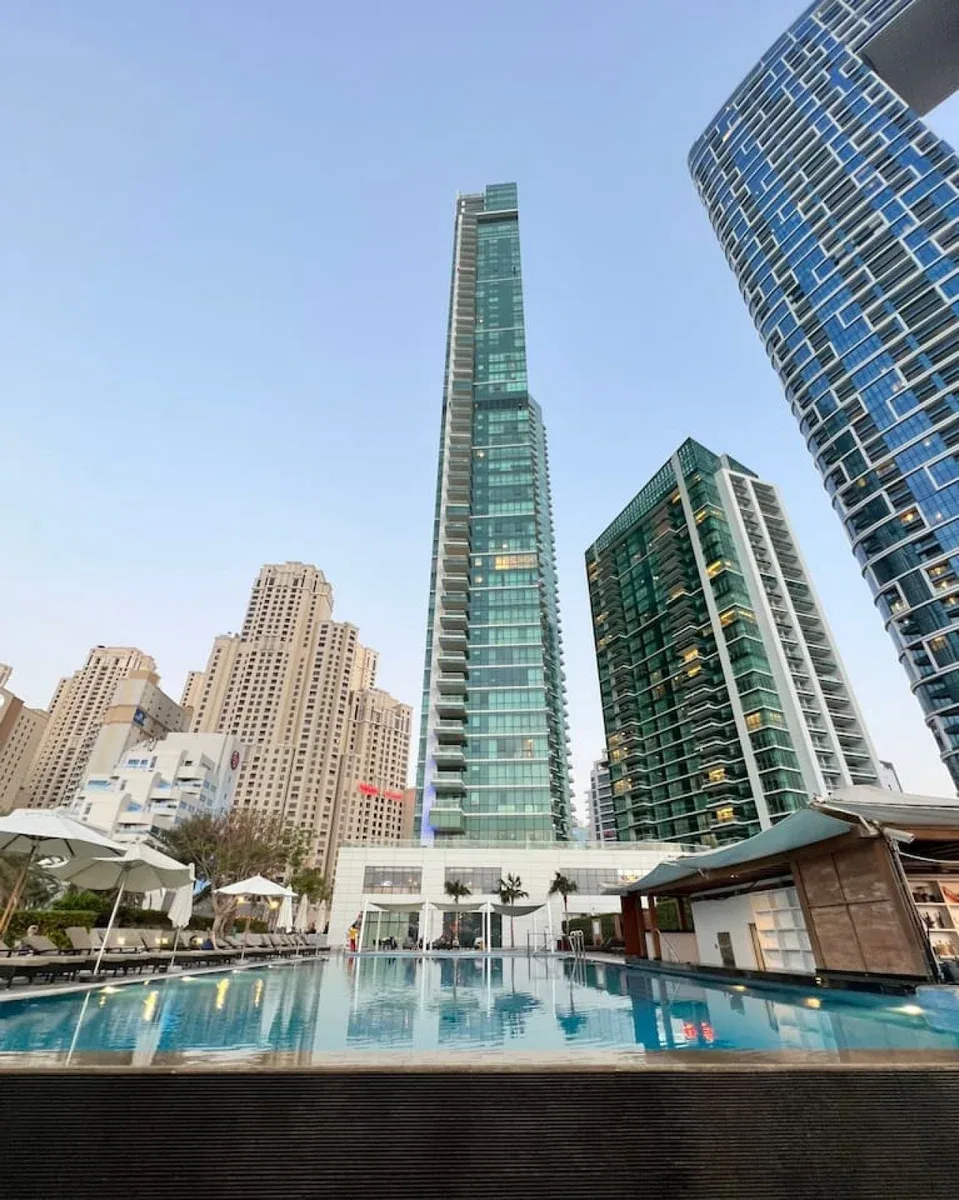 Una piscina en la azotea está rodeada de edificios altos bajo un cielo despejado.