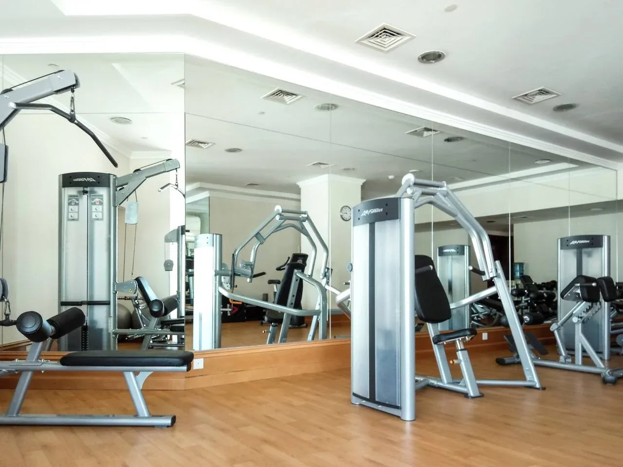 Un gimnasio con máquinas de ejercicio y espejos en las paredes.