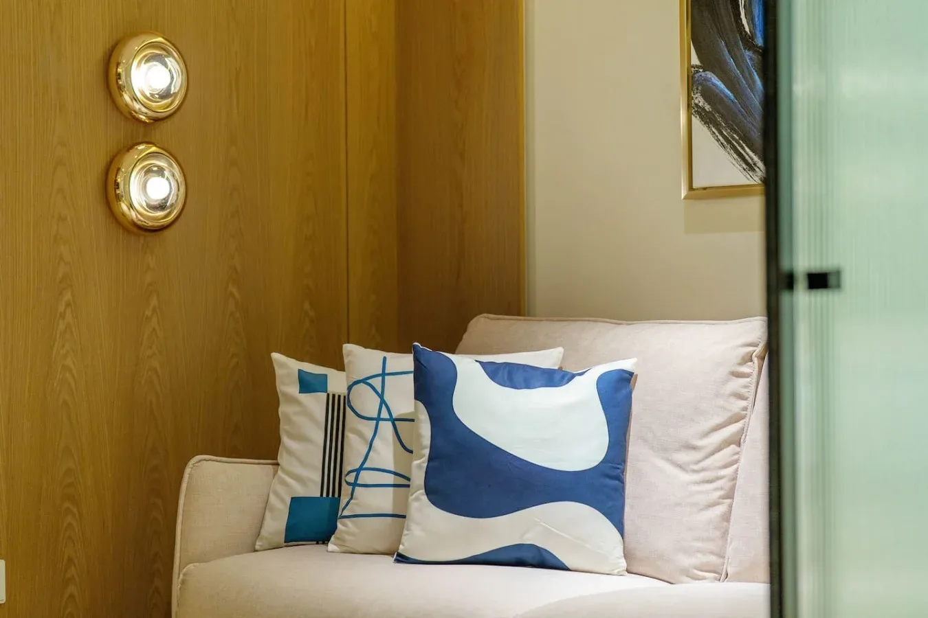 Una zona de asientos con cojines estampados en azul y blanco junto a una pared de madera.