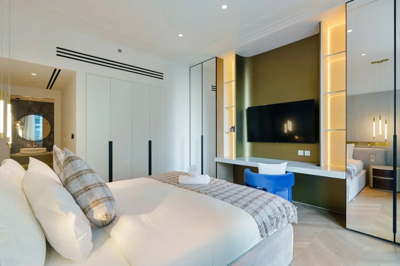 Un dormitorio con una cama grande frente a un televisor montado en la pared.