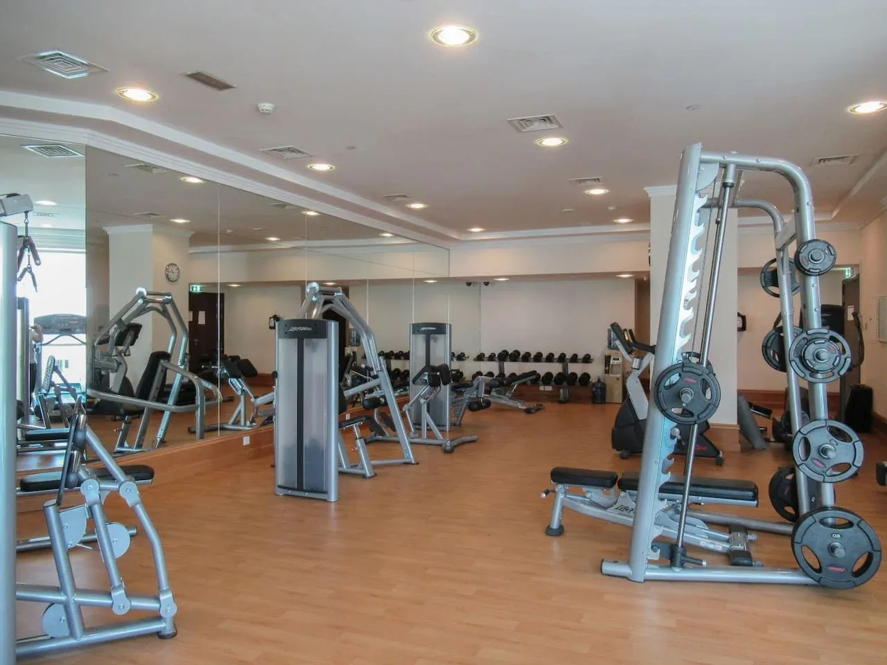 Un gimnasio con máquinas de ejercicio y pesas distribuidas por una sala amplia.