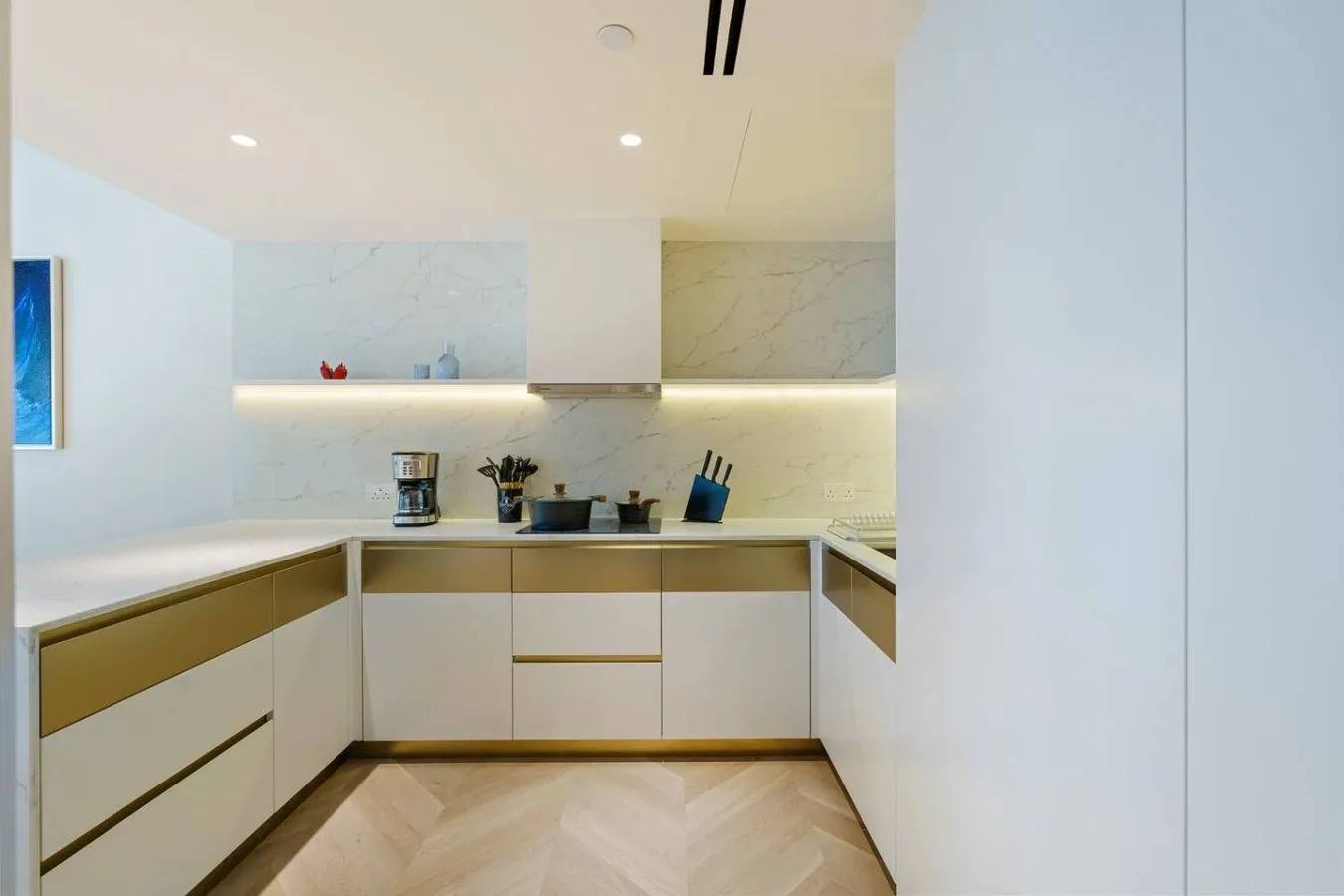 Una cocina moderna con gabinetes claros y un piso de madera pálida.