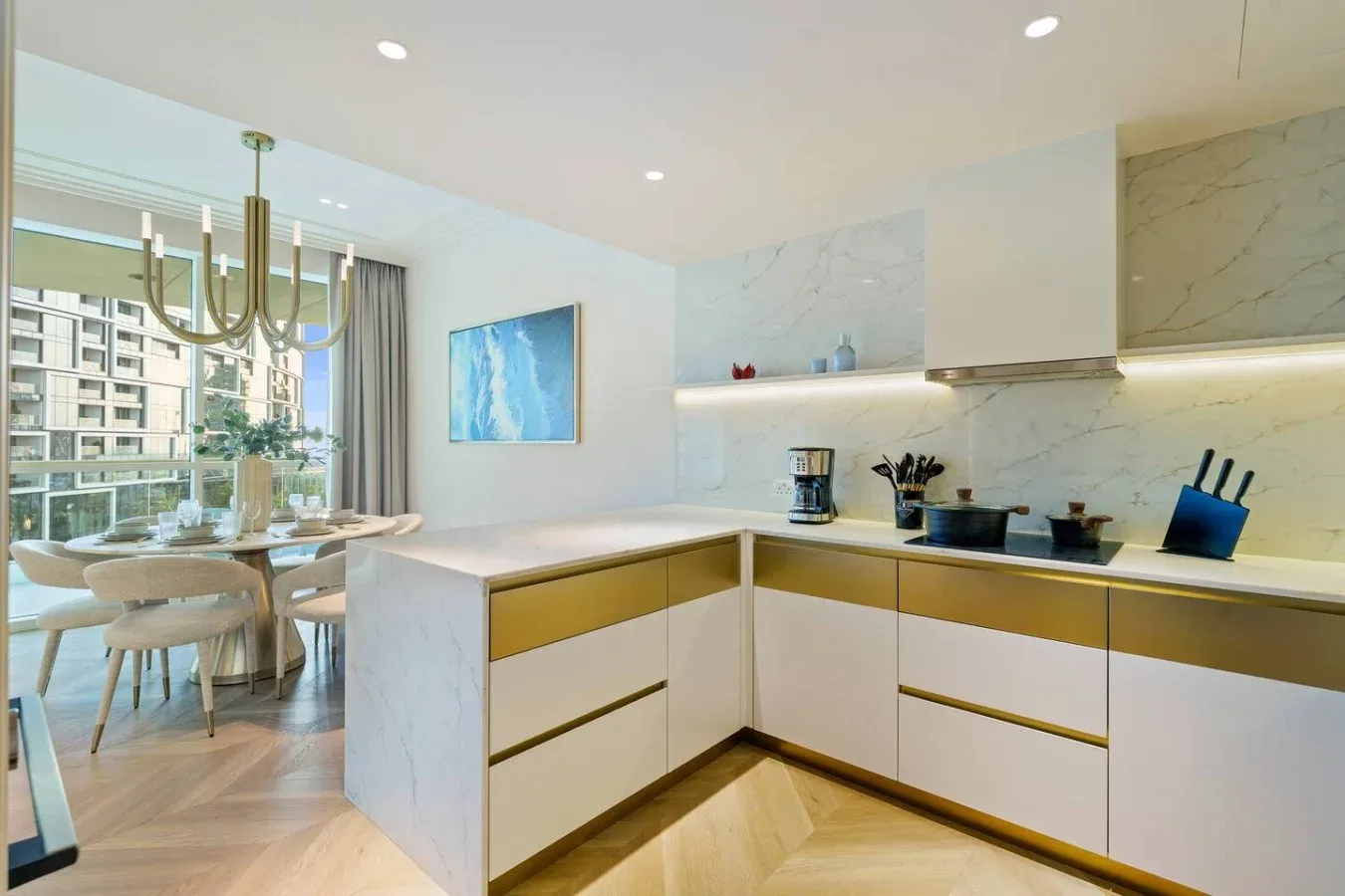 Una cocina moderna con isla y comedor junto a grandes ventanales.