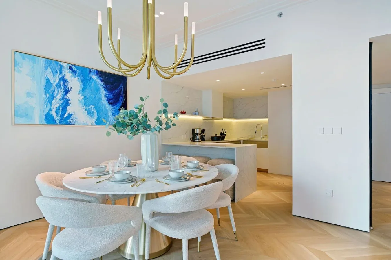 Un comedor con la mesa puesta junto a una cocina abierta.
