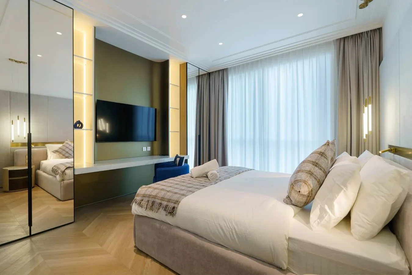 Un dormitorio con una cama grande, un televisor y cortinas de suelo a techo.
