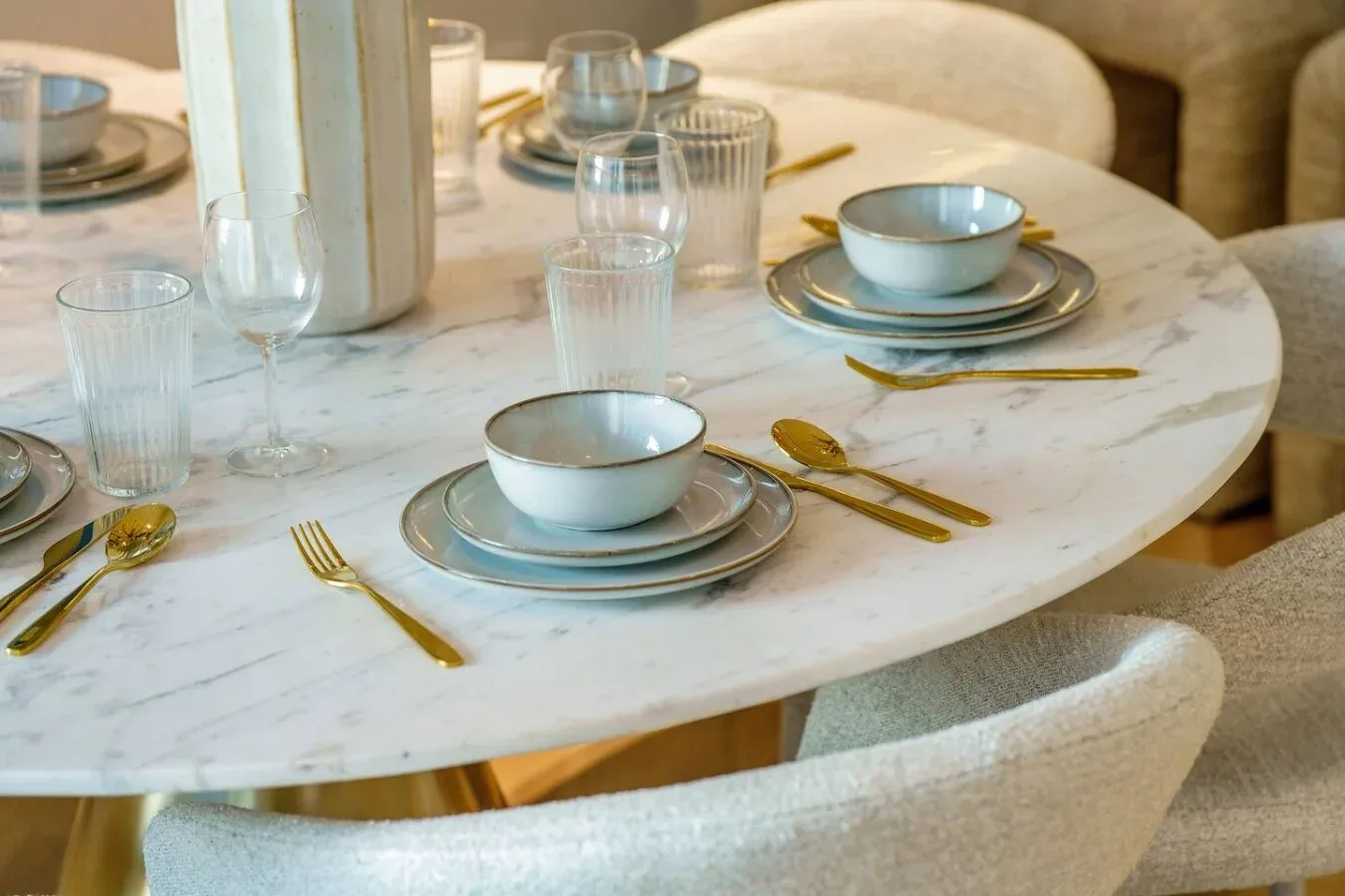 Una mesa de comedor está puesta con platos, cuencos, vasos y cubiertos.
