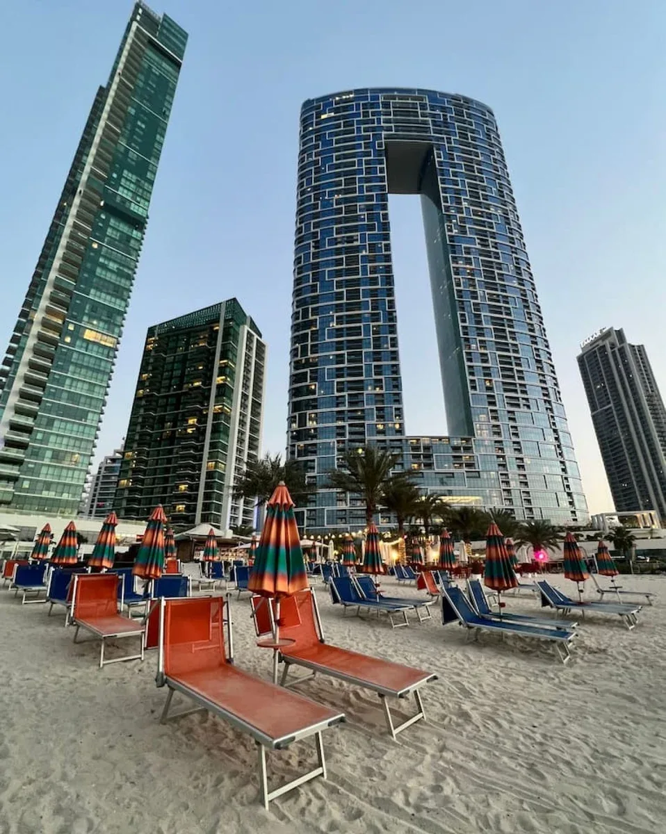 Una zona de descanso al aire libre con tumbonas y sombrillas se encuentra junto a edificios altos.