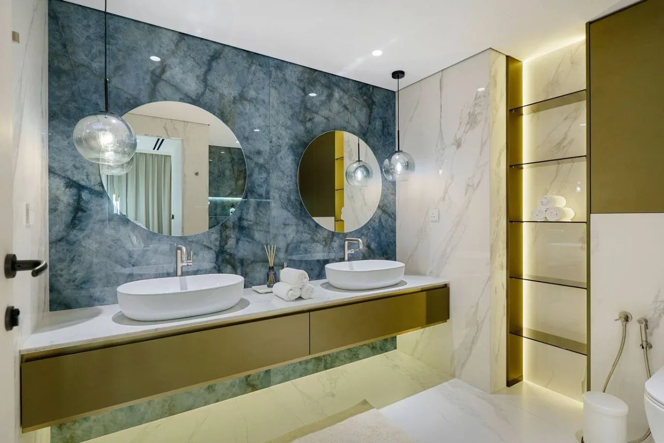 Un baño moderno con un mueble largo, dos lavabos y espejos redondos.