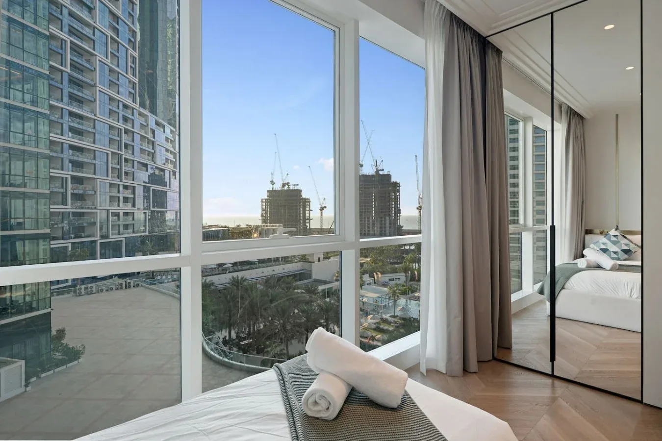 Un dormitorio con una gran ventana con vistas a edificios cercanos.